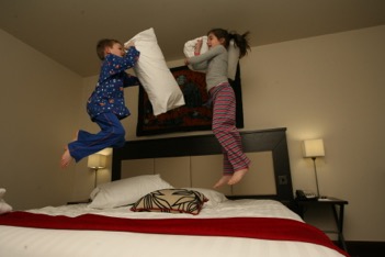 kids having a pillow fight while jumping on bed